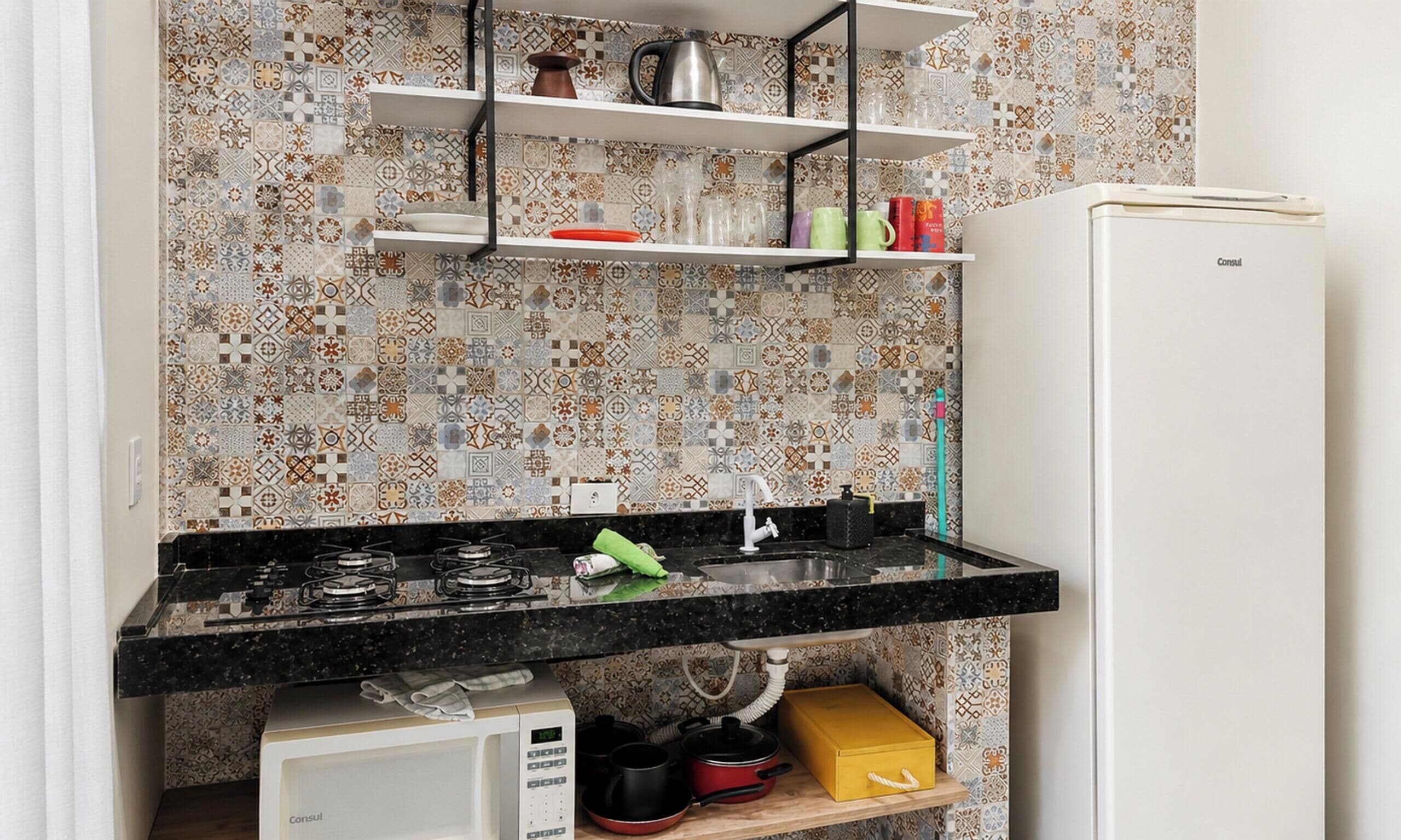 A kitchen with a black countertop, a white refrigerator, and patterned backsplash tiles.