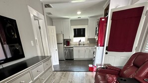 A modern kitchen with white cabinets, a stainless steel refrigerator, and a built-in dishwasher.