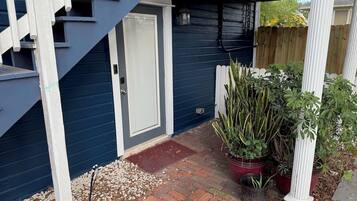 A covered porch with a staircase, a door, and potted plants.