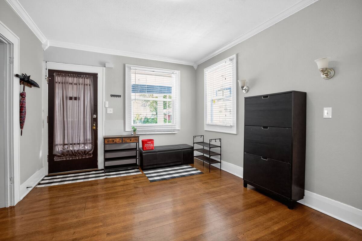 Um corredor com piso de madeira, um banco preto, uma caixa vermelha e um armário preto.