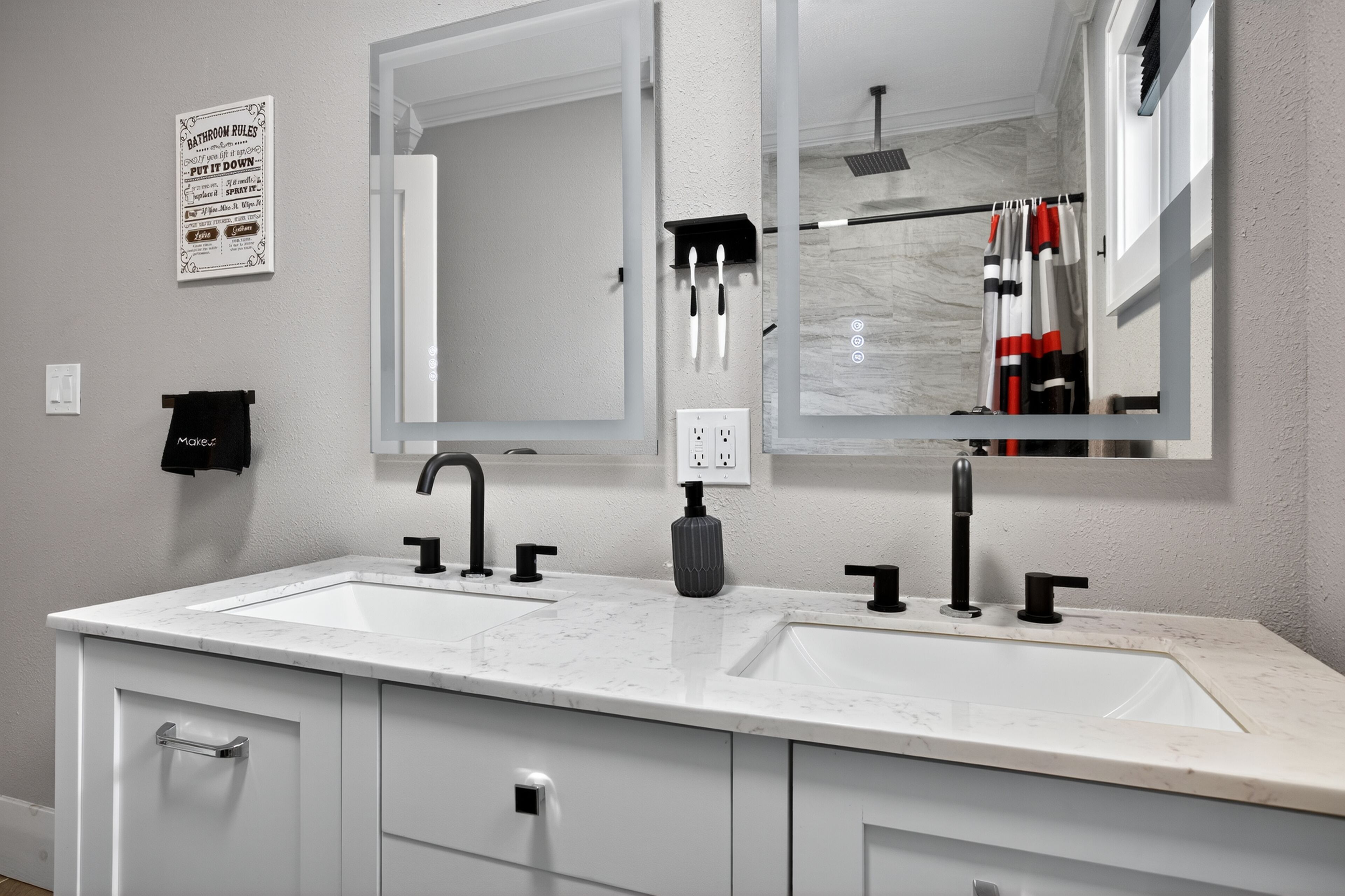 A bathroom with two sinks, a large mirror, and a towel rack.