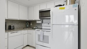 A kitchen with white cabinets, a built-in oven, a microwave, and a refrigerator. - Beachfront 1BR condo with pool, WiFi, and Gulf views. (Marco Island)