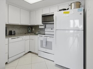 A kitchen with white cabinets, a built-in oven, a microwave, and a refrigerator. - Beachfront 1BR condo with pool, WiFi, and Gulf views. (Marco Island)