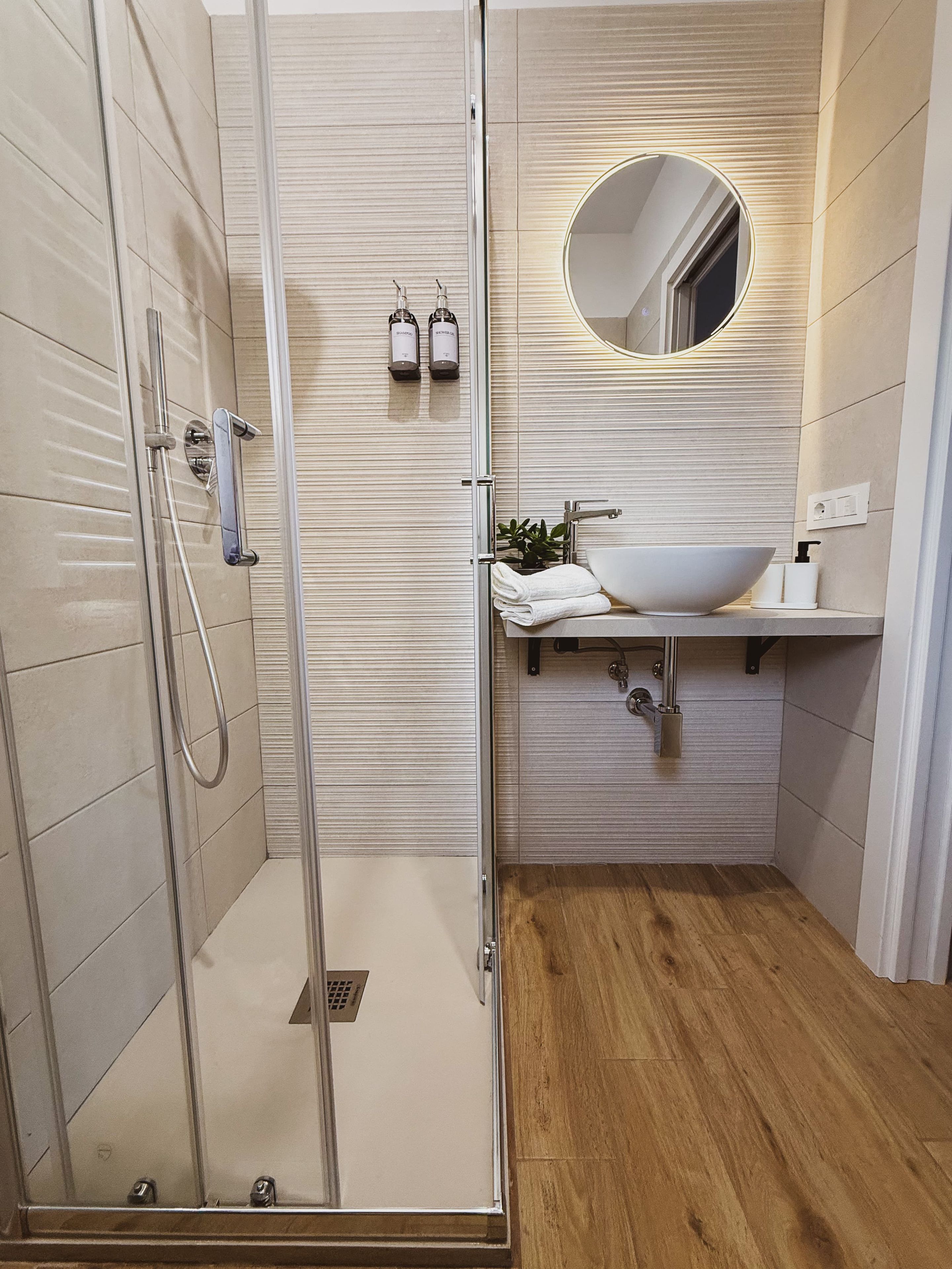 Un baño moderno con cabina de ducha de vidrio, un lavamanos blanco y un espejo.