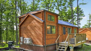 Eine Holzhütte mit einer Terrasse, einem Mülleimer und einer Klimaanlage.