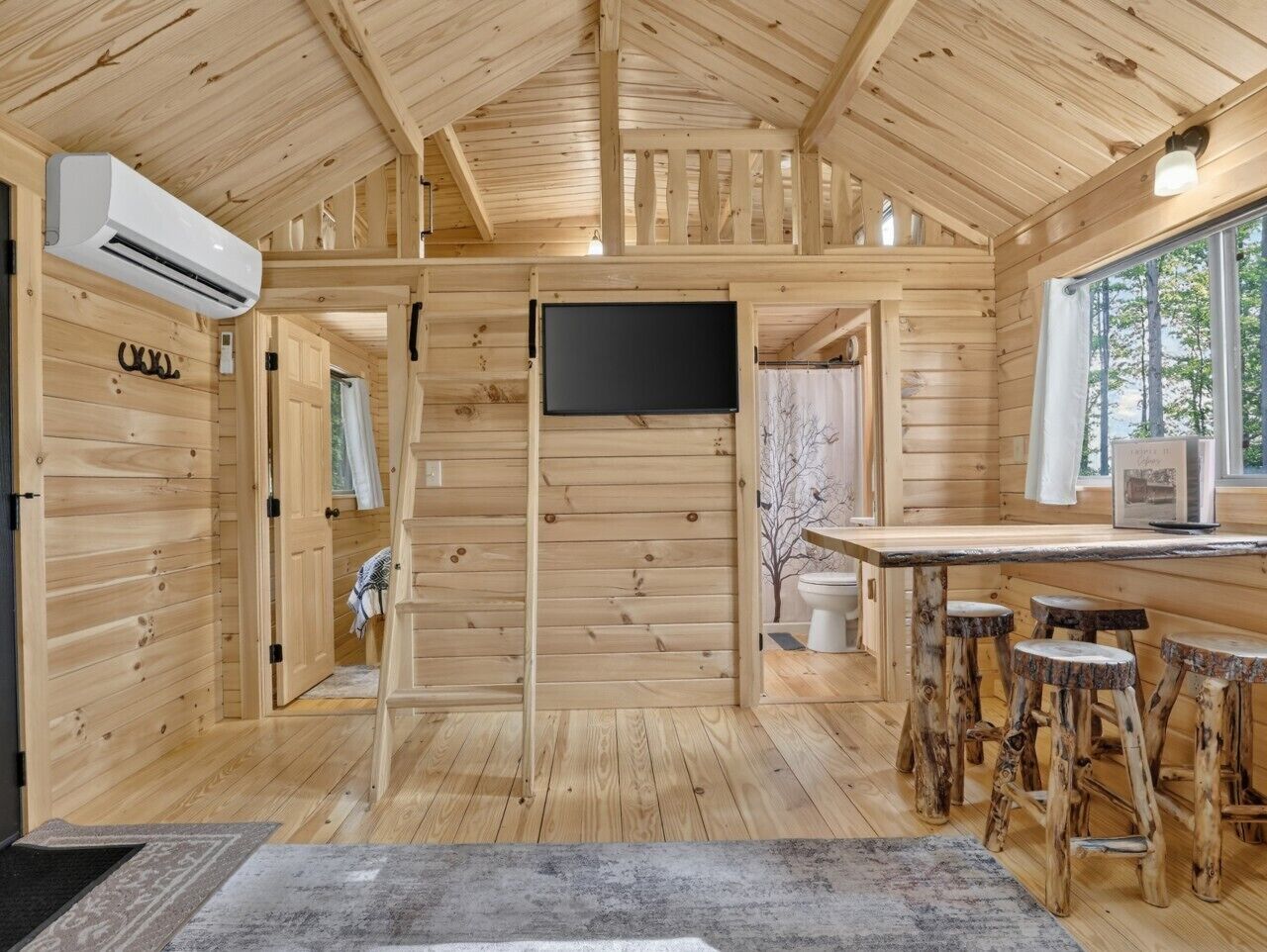 Ein Holzblockhaus-Interieur mit einer Küchenzeile, Barhocker und einem Fernseher.