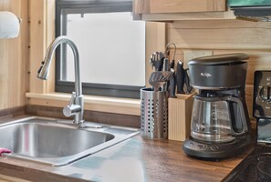 A kitchen with a stainless steel sink, a coffee maker, and a knife block. - Middlebury Center Cabins w Pond, Trails & Views! (Middlebury Center)
