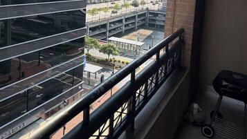 Un balcon offrant une vue sur le paysage urbain, avec des bâtiments modernes et une route où circulent des véhicules.