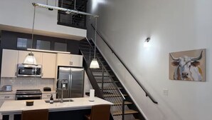 Eine moderne Küche mit Kochinsel, Edelstahlgeräten und Pendelleuchten.
