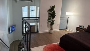 Ein modernes Schlafzimmer mit Bett, Nachttisch, Lampe und einer Topfpflanze.