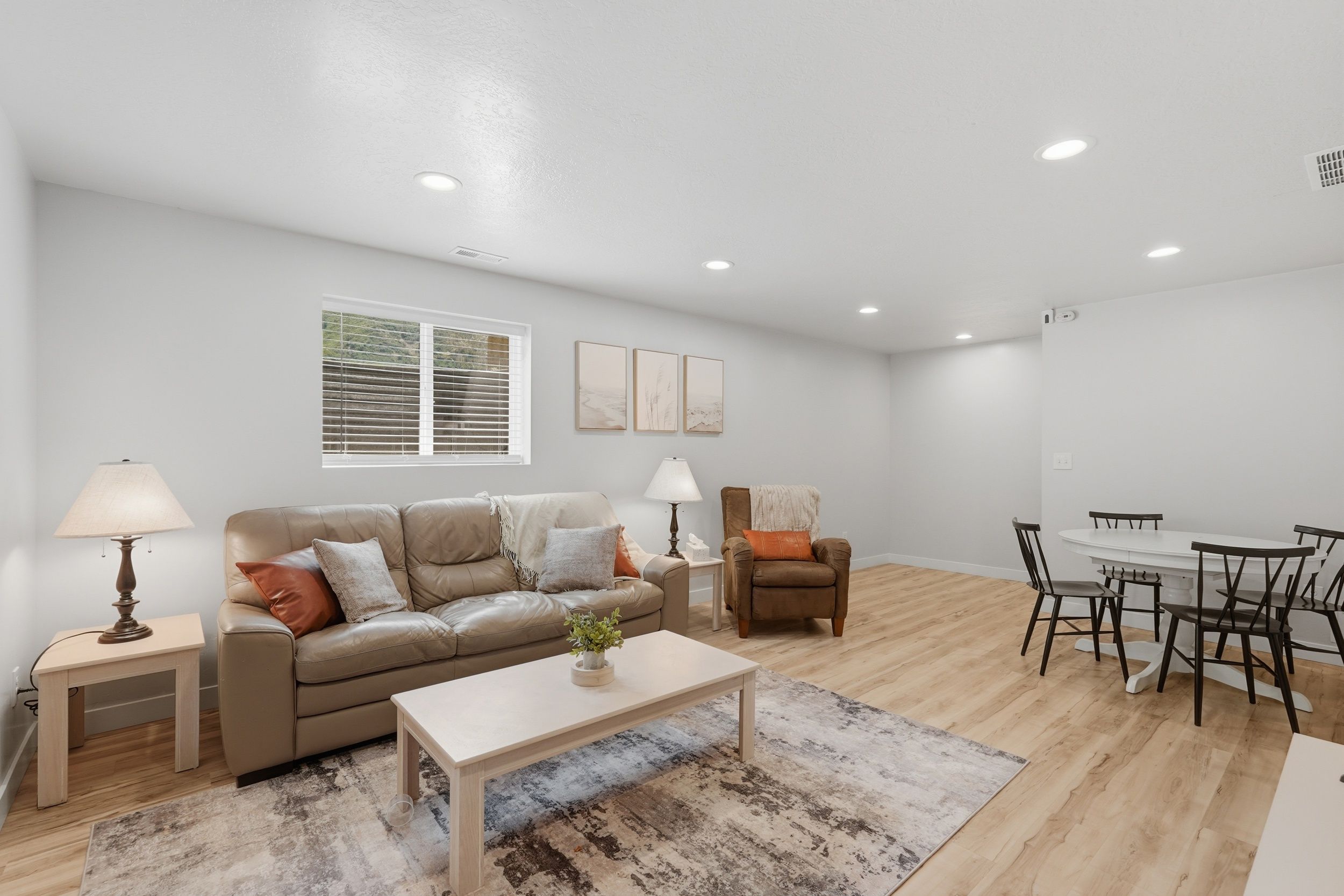 A modern living room with a sofa, coffee table, and a dining area with chairs and a table.