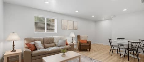 Una sala de estar moderna con sofá, mesa de centro y comedor con sillas y una mesa.
