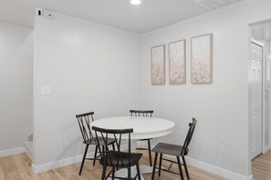 A dining area with a round table and four chairs, white walls, and three framed pictures on the wall. - Fantastic 2-bedroom apartment with AC in charming East Layton (Layton)