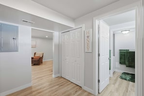Ein Flur mit einer geschlossenen Tür, einem Kleiderständer und einem gerahmten Bild an der Wand.