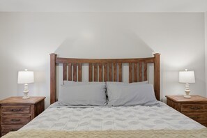 Ein Bett mit Holz Kopfteil, zwei Nachttische jeweils mit Lampen und eine gemusterte Bettdecke.