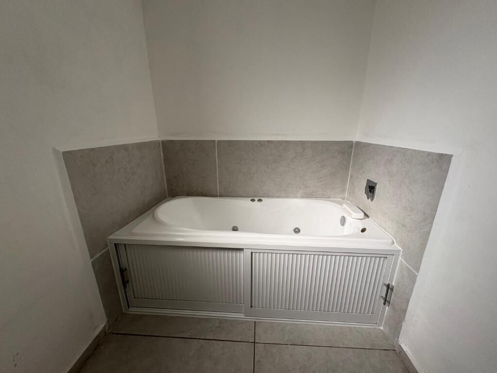 Un baño estándar con una bañera independiente, paredes y piso alicatados.