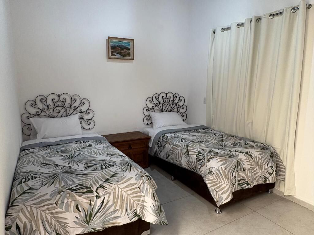 Une chambre à coucher avec deux lits, chacun doté d’une tête de lit décorative, d’une table de chevet et d’un tableau au mur.