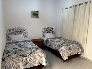 Un dormitorio con dos camas, cada una con cabecera decorativa, mesita de noche y un cuadro en la pared.