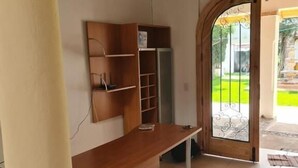 A room with a wooden bench, a built-in shelf unit, and a glass door leading outside.