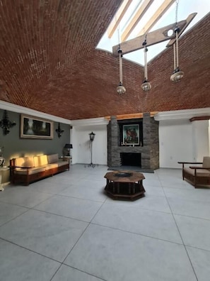 Un salón comedor amplio con techo alto, chimenea y tragaluces.
