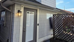 A two-story house with a grey door, a small porch with a bench, and a wooden fence. - Private Comfortable Guest House (Vancouver)