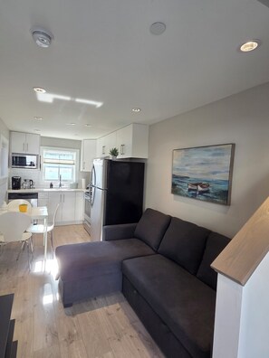 A modern kitchen with white cabinets, a black refrigerator, and a dining area with a white table and chairs. - Private Comfortable Guest House (Vancouver)
