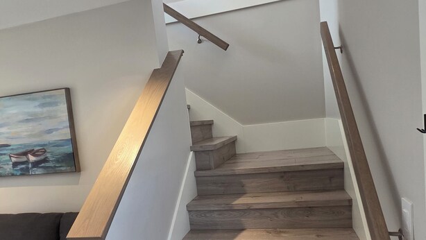 A staircase with wooden steps and a handrail, leading to a landing with a ceiling light. - Private Comfortable Guest House (Vancouver)