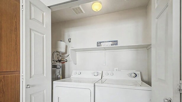 A laundry room with two stacked washers and dryers, a water heater, and a light fixture. - 2-bedroom condo with Pool, Sauna, Fitness Center and Game room.  (Phoenix)