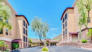 A building with a parking lot and a tree in the center. - 2-bedroom condo with Pool, Sauna, Fitness Center and Game room.  (Phoenix)