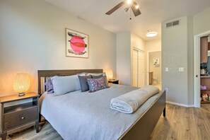 Ein Schlafzimmer mit einem Bett, Nachttischen, einem Deckenventilator und einem an der Wand hängenden Kunstwerk.