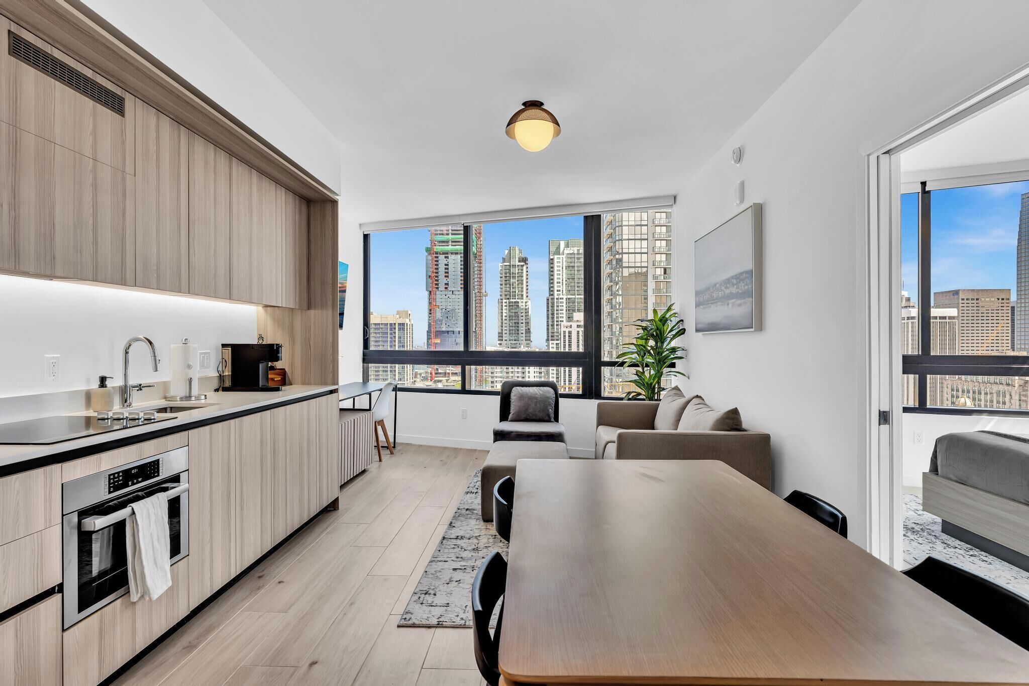 A modern apartment with a kitchen, dining area, and a large window with a city view.