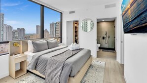 Camera da letto moderna con una grande finestra, un letto, cabina armadio e bagno con doccia in vetro.