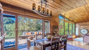 A wooden interior with a dining table, chairs, and a view of the outdoors.