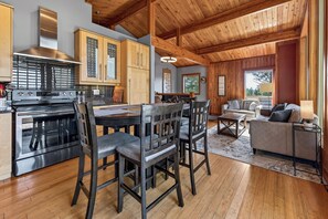 A modern kitchen with a large stove, wooden cabinets, and a dining area with a table and chairs.