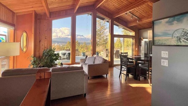 A spacious living area with wooden ceilings, large windows, and a dining area with a table and chairs. - Invermere Getaway with Stunning Views and Hot Tub! (Invermere)
