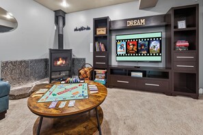 A living room with a fireplace, a television mounted on a wall, and a coffee table with board games.