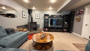 A living room with a sofa, a coffee table, a fireplace, a television, and a bookshelf. - Invermere Getaway with Stunning Views and Hot Tub! (Invermere)