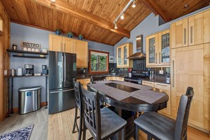 A modern kitchen with wooden cabinets, a stainless steel refrigerator, and a dining area with a round table and chairs.