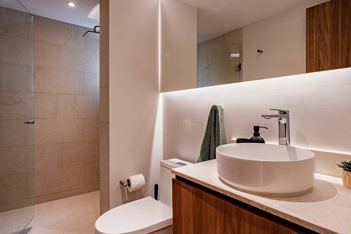 Ein modernes Badezimmer mit einem großen Spiegel, einem runden Waschbecken und einer Toilette.