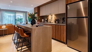 A modern kitchen with a stainless steel refrigerator, wooden cabinets, and a bar area with stools. - 3 Private Apts in Condesa with Private Terrace (Mexico City)