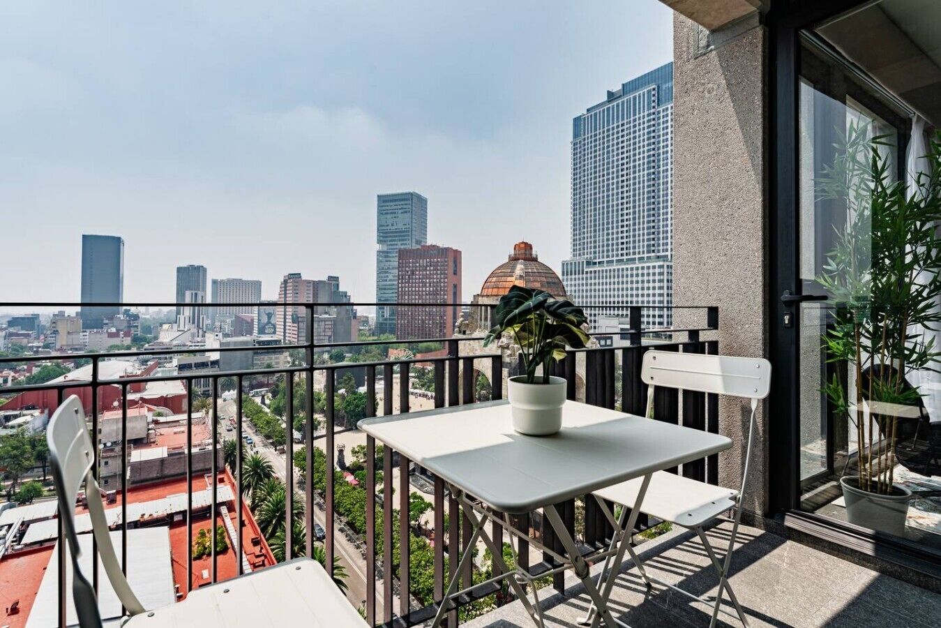 Un balcon avec une table, des chaises et des plantes en pot.