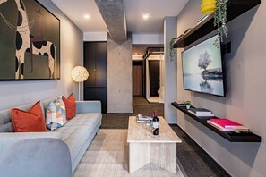 Ein modernes Wohnzimmer mit einer Couch, einem Couchtisch und einem Flachbildfernseher.