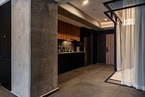 Eine moderne Küche mit einer Betonstütze, Holzschränken und einem Edelstahl-Kühlschrank.