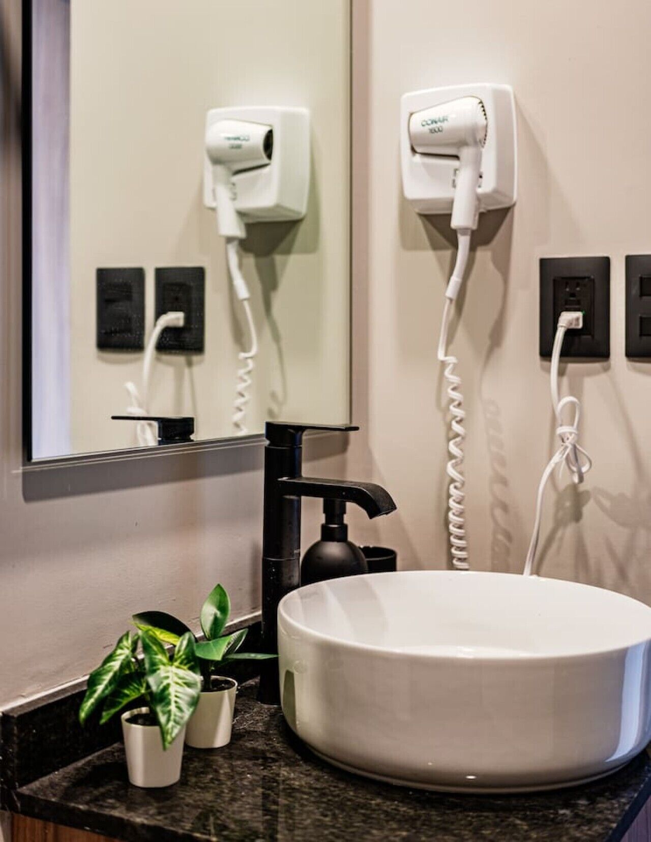 Een badkamer met een rond wastafel, een haardroger en een spiegel.