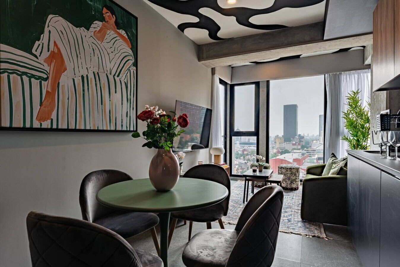 A modern living room with a dining area, a large window with a city view, and a painting on the wall.