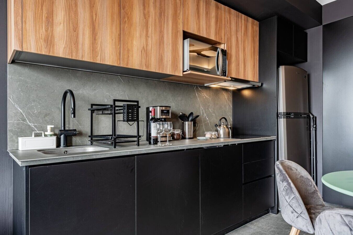 Uma cozinha moderna com micro-ondas embutido, máquina de café e chaleira no balcão.