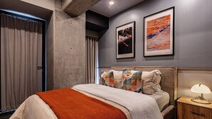 A modern hotel room with a large bed, a nightstand with a lamp, and two framed artworks on the wall. - Stylish Stay Across from Monumento a la Revolución (Mexico City)