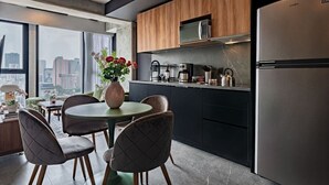 A modern kitchen with a built-in microwave, coffee maker, and kettle, a dining area with a round table and chairs, and a large window with a city view. - Stylish Stay Across from Monumento a la Revolución (Mexico City)