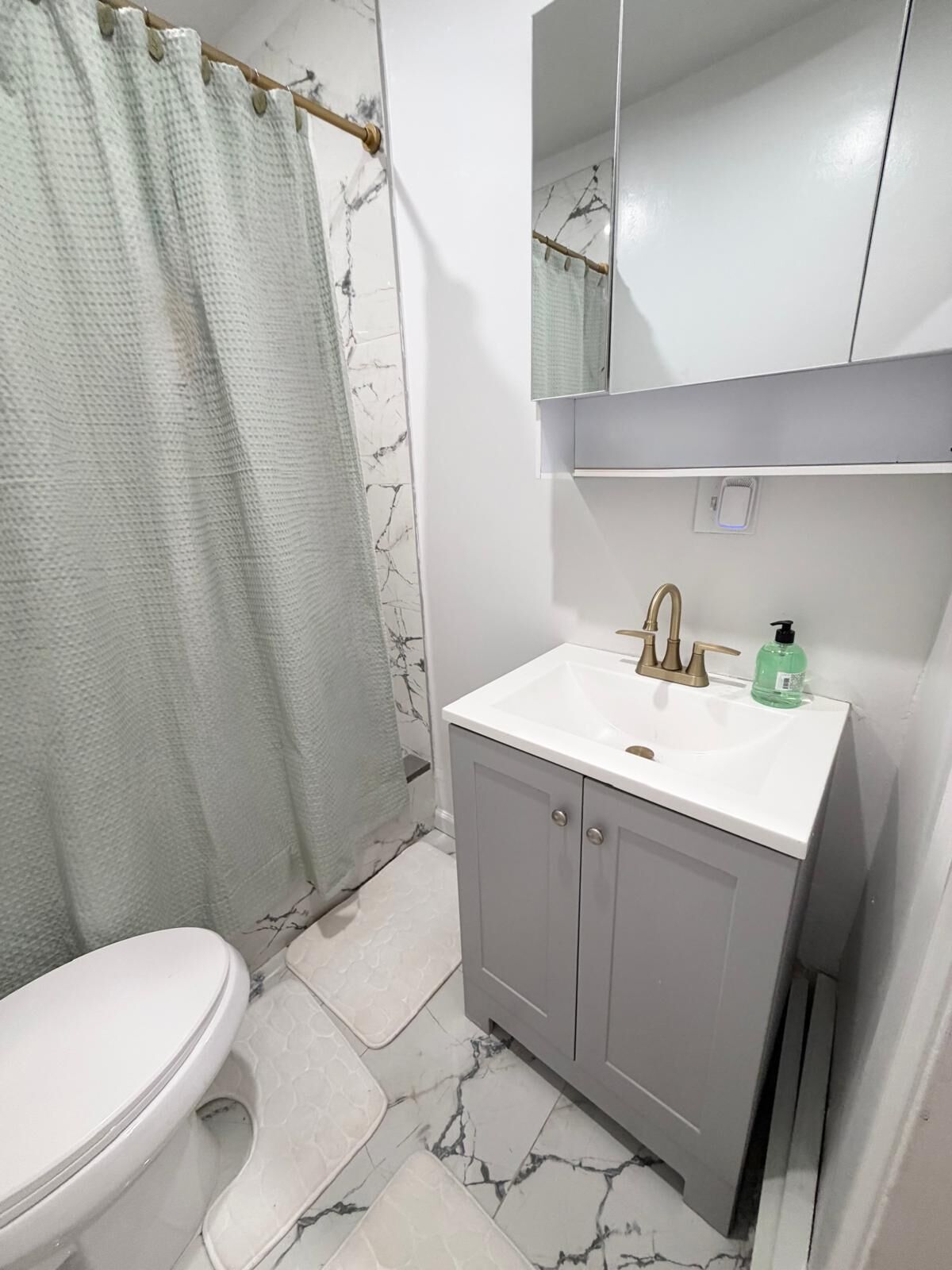 A bathroom with a toilet, a sink with a mirror above it, and a shower curtain.