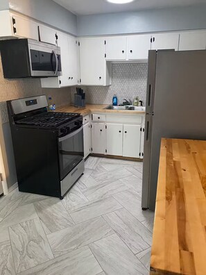 Eine Küche mit weißen Schränken, einem Edelstahlherd und einer Holz Arbeitsplatte.